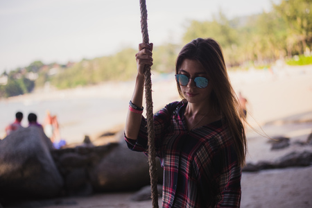 Cute girl posing on a beach. She holds a rope and looking far away. Perfect photo for a fashion storeの写真素材