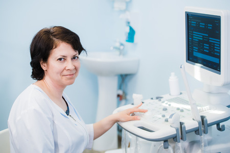 Happy mature female doctor using ultrasound scanner. Echography machineの写真素材