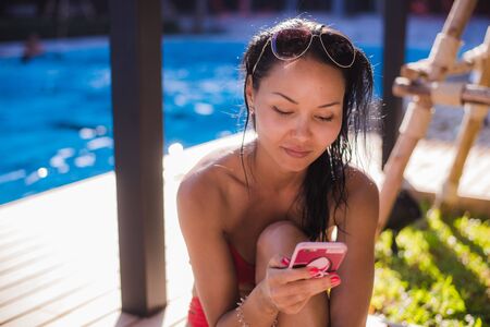 Beautiful woman working on her communications poolside on holidayの写真素材