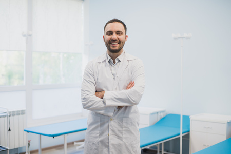 Portrait of a happy male doctor standing with arms crossed at medical officeの写真素材