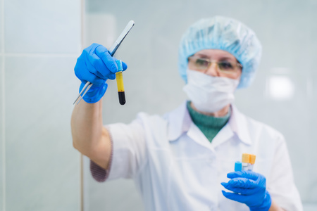 Closeup of a senior female chemist setting up some sample blood tubes inside a centrifuge for some test in a lab.の写真素材