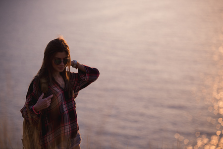 Woman traveler looks at the edge of the cliff on the sea bay of mountains in the background at...