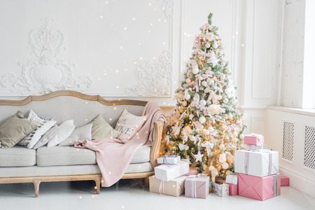 New Year's holiday or celebration, the mood, Stylish Christmas minimalistic interior, Presents and wrapped gifts under the Christmas tree. large white living room with a vintage sofa.の写真素材