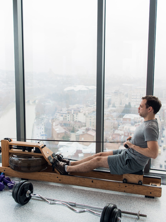 Man working out on row machine in fitness studio at scyscraper luxury hotel gymの写真素材