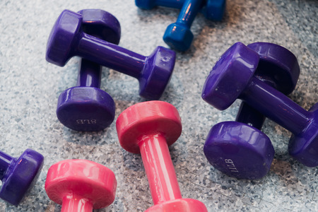 Purple and pink dumbbells lie on the gray floor at gymの写真素材