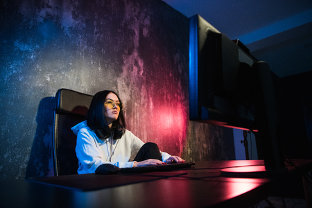 young attractive teen woman eyeglasses on looking dark and dangerous hacking computer system on black background in cybercrime or cyber crime and internet criminal conceptの写真素材