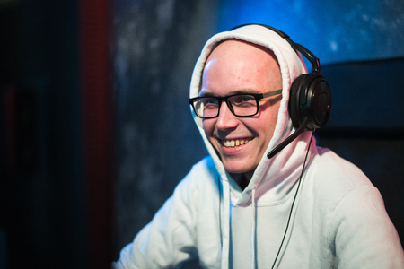 technology, gaming, entertainment, lets play and people concept - happy young man in eyeglasses with headset playing and winning computer game at home and streaming playthrough or walkthrough videoの写真素材