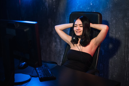 Young excited girl gamer winning video game sitting on a chair at home. Female player playing videogames at homeの写真素材