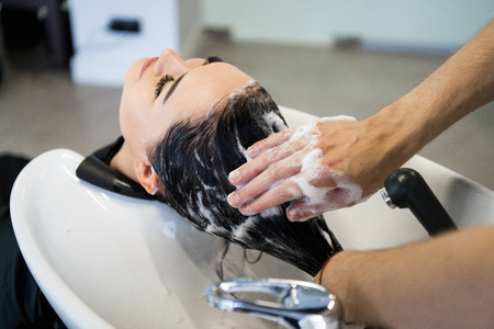 Female client getting hair washed by hairstylist in parlorの写真素材