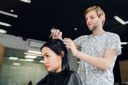 Hairdresser creating a hairstyle for beautiful woman closeupの写真素材
