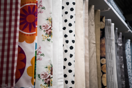 Colorful curtain samples hanging from hangers on rail in a display retail store Multiple color fabric texture samples selection fabrics for interior decoration Curtains,tulle and furniture upholstery.の写真素材