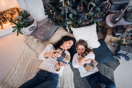 Mother and daughter lying with gifts under Christmas tree, top viewの写真素材