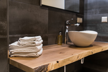 Stacked white spa towels on wooden table at modern bathroomの写真素材
