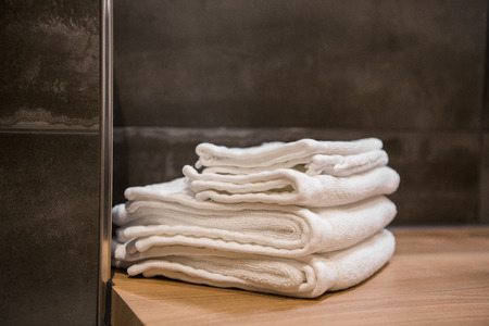 Stacked white spa towels on wooden table at modern bathroomの写真素材