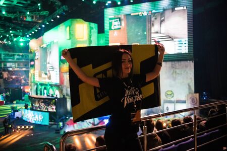 MOSCOW, RUSSIA - OCTOBER 27 2018: EPICENTER Counter Strike: Global Offensive esports event. Happy girl fan on a tribune at arena with team Natus Vincere flag. Cheering for her favorite team.のeditorial素材
