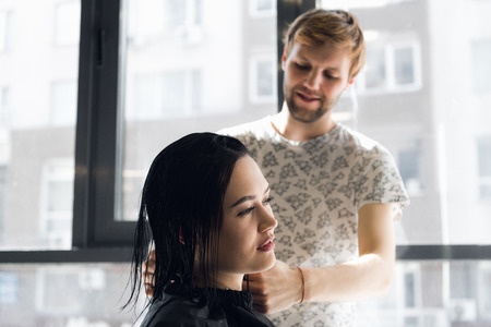 Smiling woman getting haircut by handsome hairdresserの写真素材