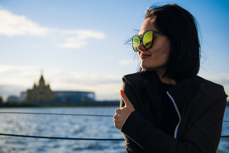 Beautiful female enjoying her free time by the river. Girl Outdoor Lifestyle. Young woman with black hair wearing sunglasses.の写真素材