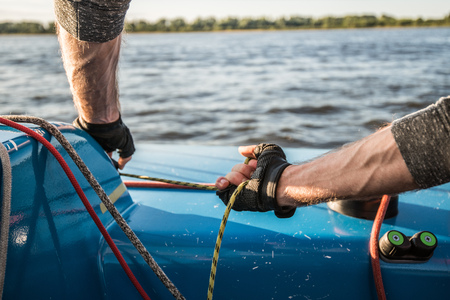 Silhouette of a sailors hands on a winch rope on a sailboat on a sunset. Shot with a selective focus.の写真素材