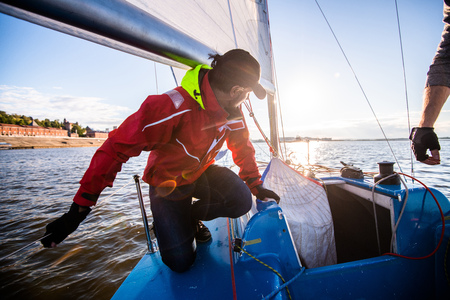Beautiful inspiring shot of action adventure of sailor or captain on yacht or sailboat attaching big mainsail or spinnaker with ropes on deck of boat, sunny summer adventure lifestyleの写真素材