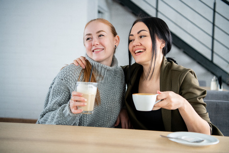 Two young and beautiful women meet at the bar for a cappuccino and to chat.の写真素材