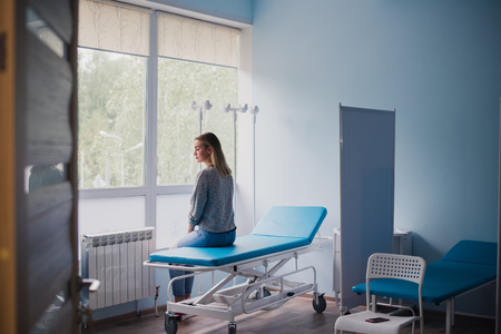 Waiting patient. A woman waiting for medical examination by sitting on treatment couchの写真素材