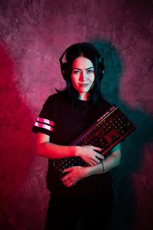 Young teen gamer wearing glasses standing posing with computer gaming equipmentの写真素材