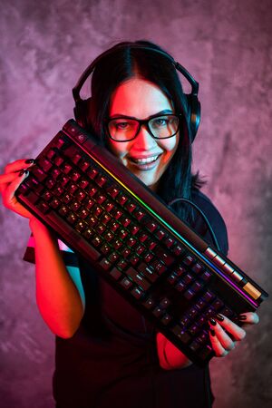 Funny nerd girl wearing glasses carrying computer keyboardの写真素材