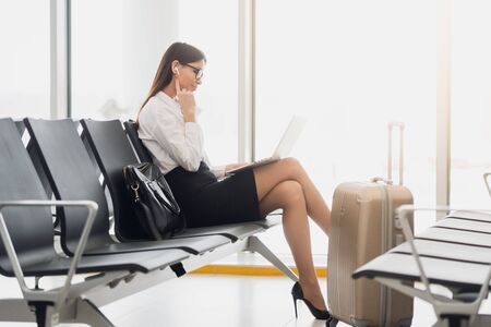 Businesswoman Using Laptop In Airport Departure Loungeの写真素材