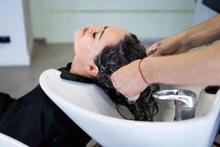 Beautiful young girl washing her head in a beauty salon.