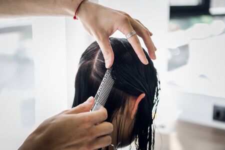 Hairdresser working in hair salon cutting woman's hair.の写真素材