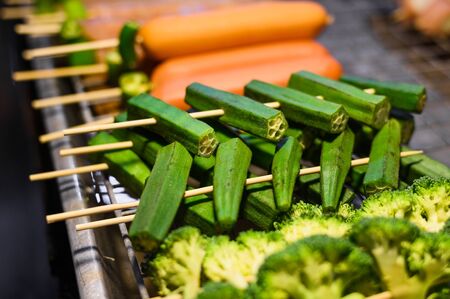 Broccoli and carrot on skewers for barbecue at food market in Thailand. Popular Asian food. Photo taken in low light at night.の写真素材