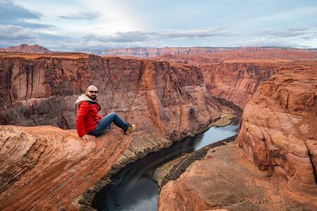 Man sitting on a cliff over Colorado river in Horseshoe bend canyonの写真素材
