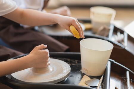 Female potter makes a pot on the pottery wheel close-up.の写真素材