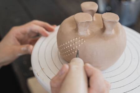 Young woman attaching clay product part to future ceramic product. Pottery workshop.の写真素材