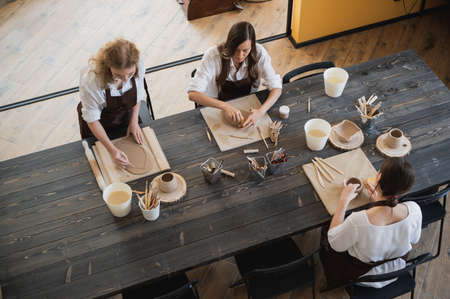 Beautiful young female artist girls creating handmade pottery in modern art studio. Education kids and parents.の写真素材