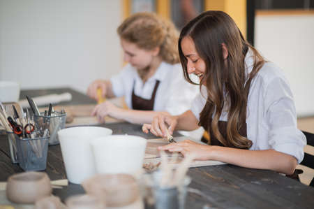 Beautiful young female artist girls creating handmade pottery in modern art studio. Education kids...