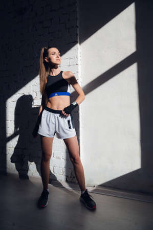 A pretty long-haired brunette of athletic build stands against a brick wall in the loftの写真素材