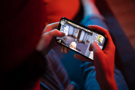 MOSCOW, RUSSIA - December 6, 2019: Girl playing PUBG FPS game on smartphone. Teenager into mobile gamingのeditorial素材