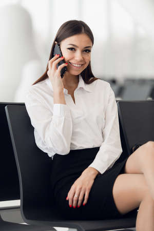 Business woman on her smart phone waiting at the airportの写真素材