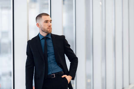 Portrait of young confident stylish business man with crossed hands near window.の写真素材