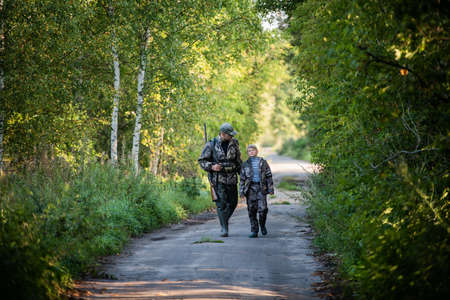 A young boy on the hunt with an experienced instructor in the forest. Autumn. Hunting for upland wildfowl.の写真素材