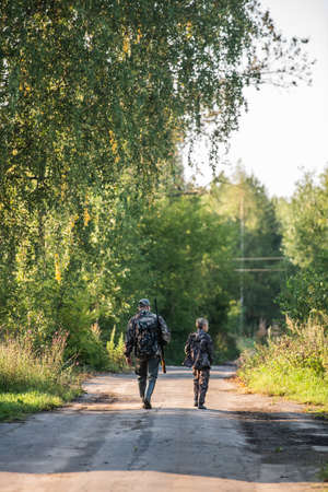 Fathers day. Father with gun showing something to son while hunting on a nature. Happy family, Fathers Day and local summer vacationの写真素材