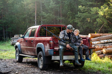 Young hunter boy sit with his father in a truck tailgateの写真素材