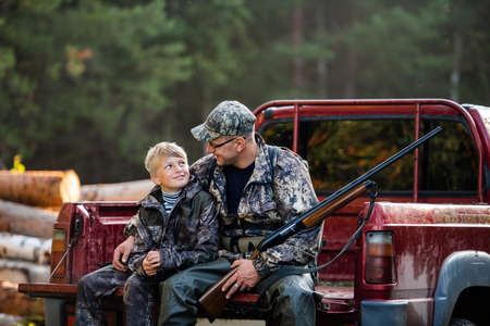 Young hunter boy sit with his father in a truck tailgateの写真素材