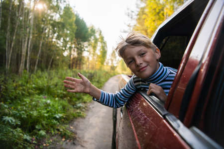 Cheerful child who is looking out of an open window of the carの写真素材
