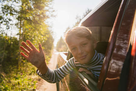 Cheerful child who is looking out of an open window of the carの写真素材