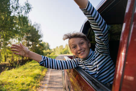 Cheerful child who is looking out of an open window of the carの写真素材