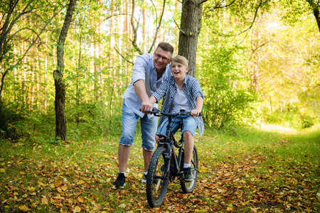 Father Teaching Son To Ride Bike In Countrysideの写真素材