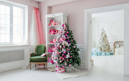 Beautiful holdiay decorated rooms with Christmas trees, shelf and pink blue gifts on it, green chair home interiorの写真素材