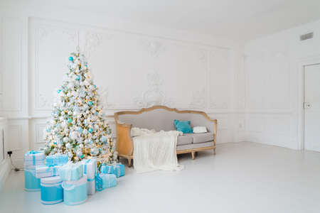 Stylish Christmas interior with an elegant sofa. Comfort home. Presents gifts underneath the tree in living roomの写真素材